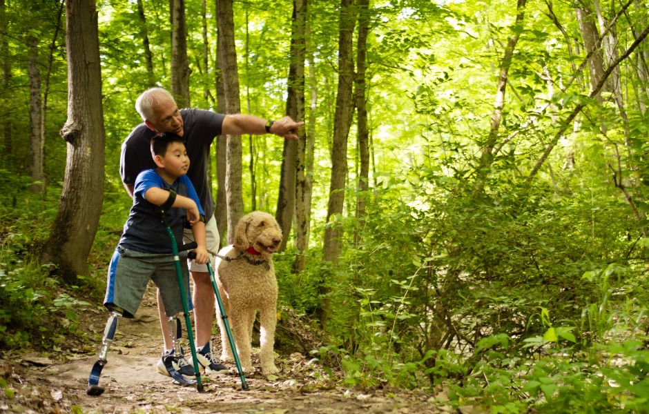 Child hiking with crutches and an elderly man with a dog. 